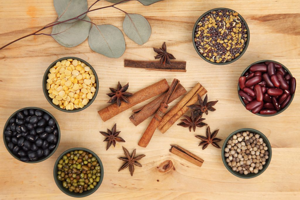 Spices laid out with cinnamon and star anise overhead looking down on wood, bay leaves at the top