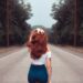 Woman walking down a road with red hair and learning how to walk like a model