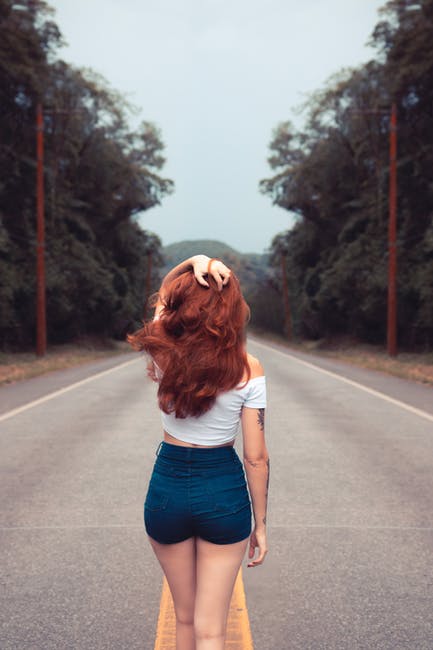 Woman walking down a road with red hair and learning how to walk like a model