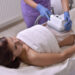Pretty young woman getting cryolipolyse treatment in cosmetic cabinet and asking how much does coolsculpting cost