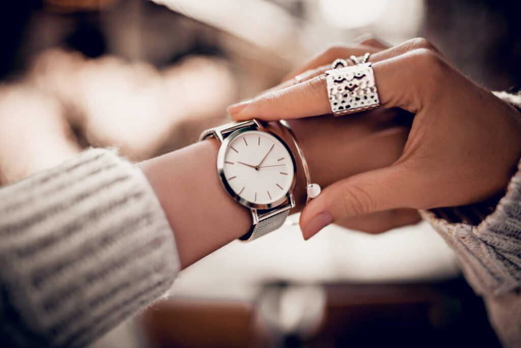 Silver watch on woman hand showing how to wear jewelry