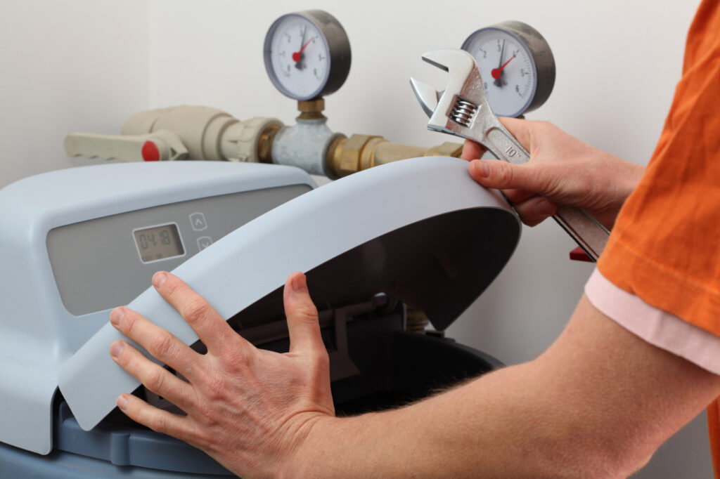 Repairing water softener, plumber with a wrench as thinking what is a water softener