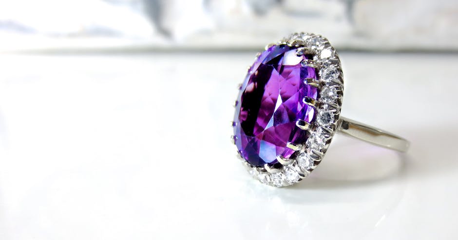 Large amethyst/purple gemstone ring with white stones around for a guide to buying gemstones