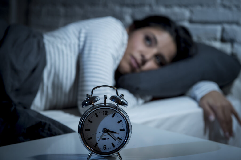 young beautiful hispanic woman at home bedroom lying in bed late at night trying to sleep suffering insomnia sleeping disorder or scared on nightmares looking sad worried and stressed