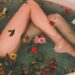 Bath filled with flowers and petals and showing a pair of naked legs and skin silky soft