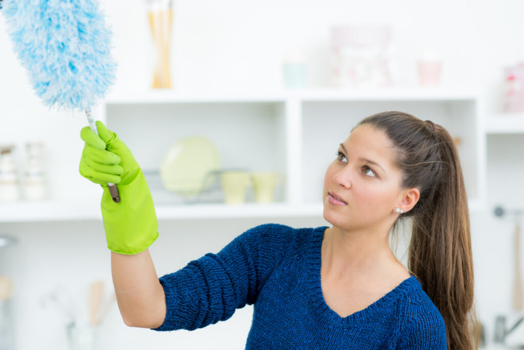 Woman cleaning with a feather duster to reduce dust