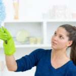 Woman cleaning with a feather duster to reduce dust