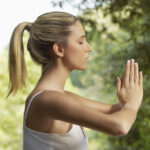Woman meditating outside with her hands in a prayer position