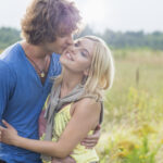 Couple stood in a fiels and the male kissing the female 5 Ideas For Frugal Dating - Can You Date On A Budget?