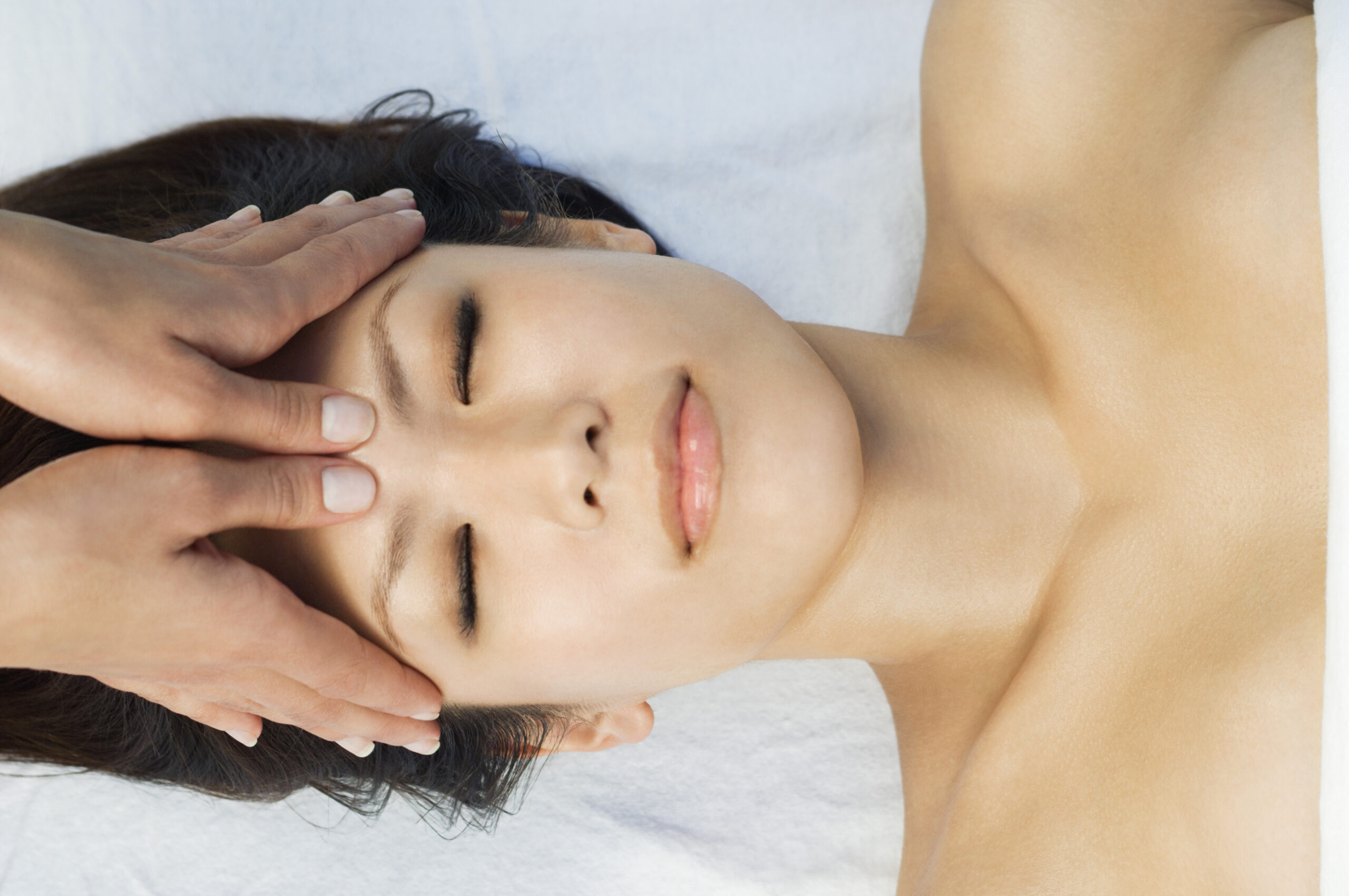 Young woman having head massage at health spa total facial rejuvenation