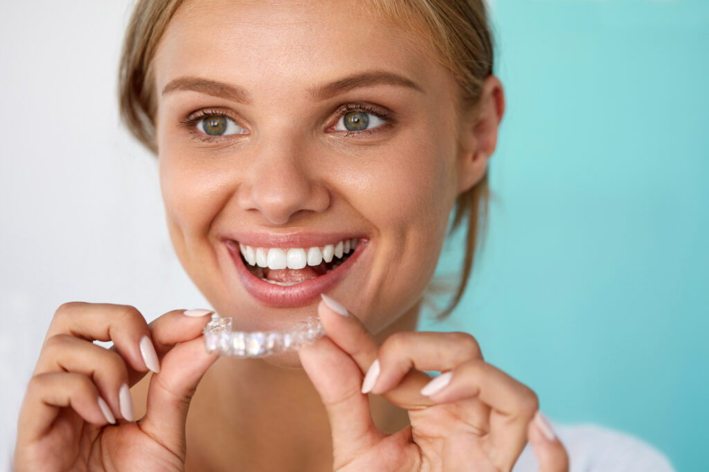 5 Common Invisalign Mistakes and How to Avoid Them Smiling Woman With Beautiful Smile Using Teeth Whitening Tray. High Resolution Image