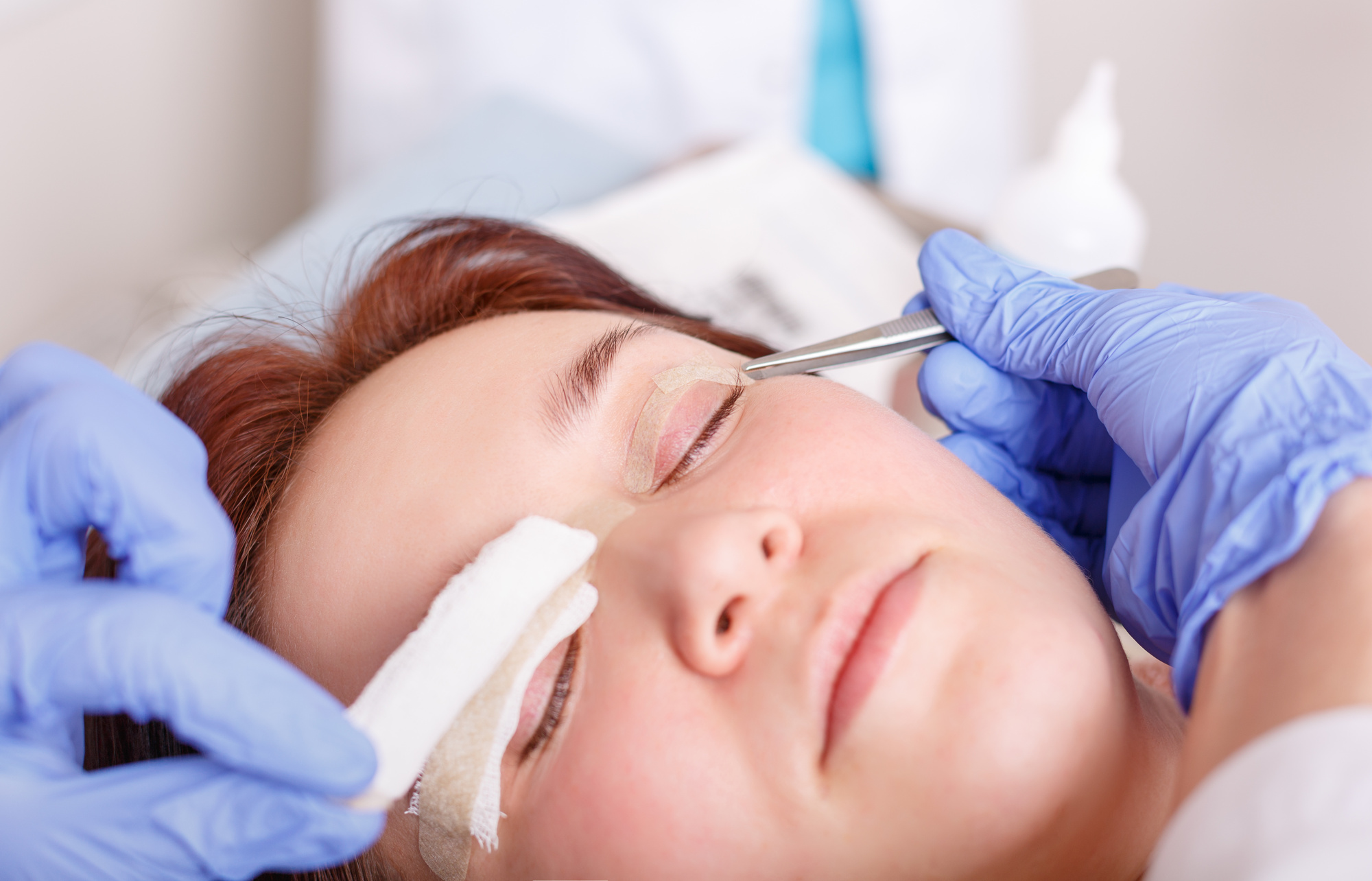 What Is Blepharoplasty? Surgeon applies a bandage to the female patient's eyelids after a blepharoplasty operation